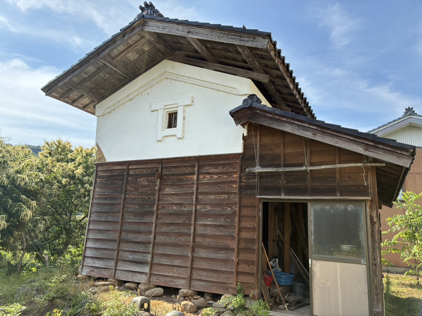 解体前の土蔵。屋根と白い漆喰の壁が残る、蔵全体の外観